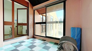 Una habitación con piso a cuadros, un amplio ventanal corredero y vistas a edificios.