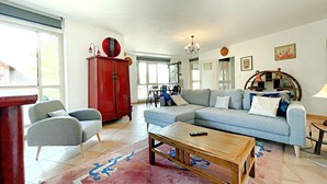 Una sala de estar con un sofá modular, un armario rojo y un comedor con sillas y una mesa.