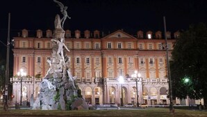 A large, classical building with a prominent statue in front.