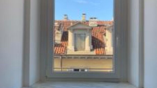 A window with a view of a building with red-tiled roofs.