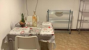 A dining area with a table set for two, a television mounted on the wall, and a clock.