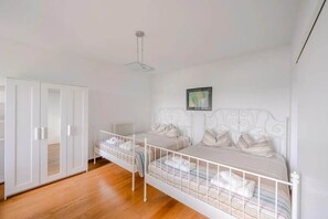 Une chambre avec deux lits, une armoire et un radiateur.