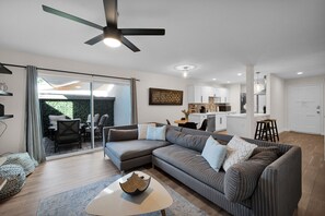 A modern living room with a sectional sofa, a coffee table, and a dining area with a table and chairs.