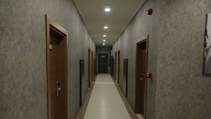 A long, narrow hallway with doors on both sides, leading to individual rooms. - ELİT OTELHAN (Amasya)