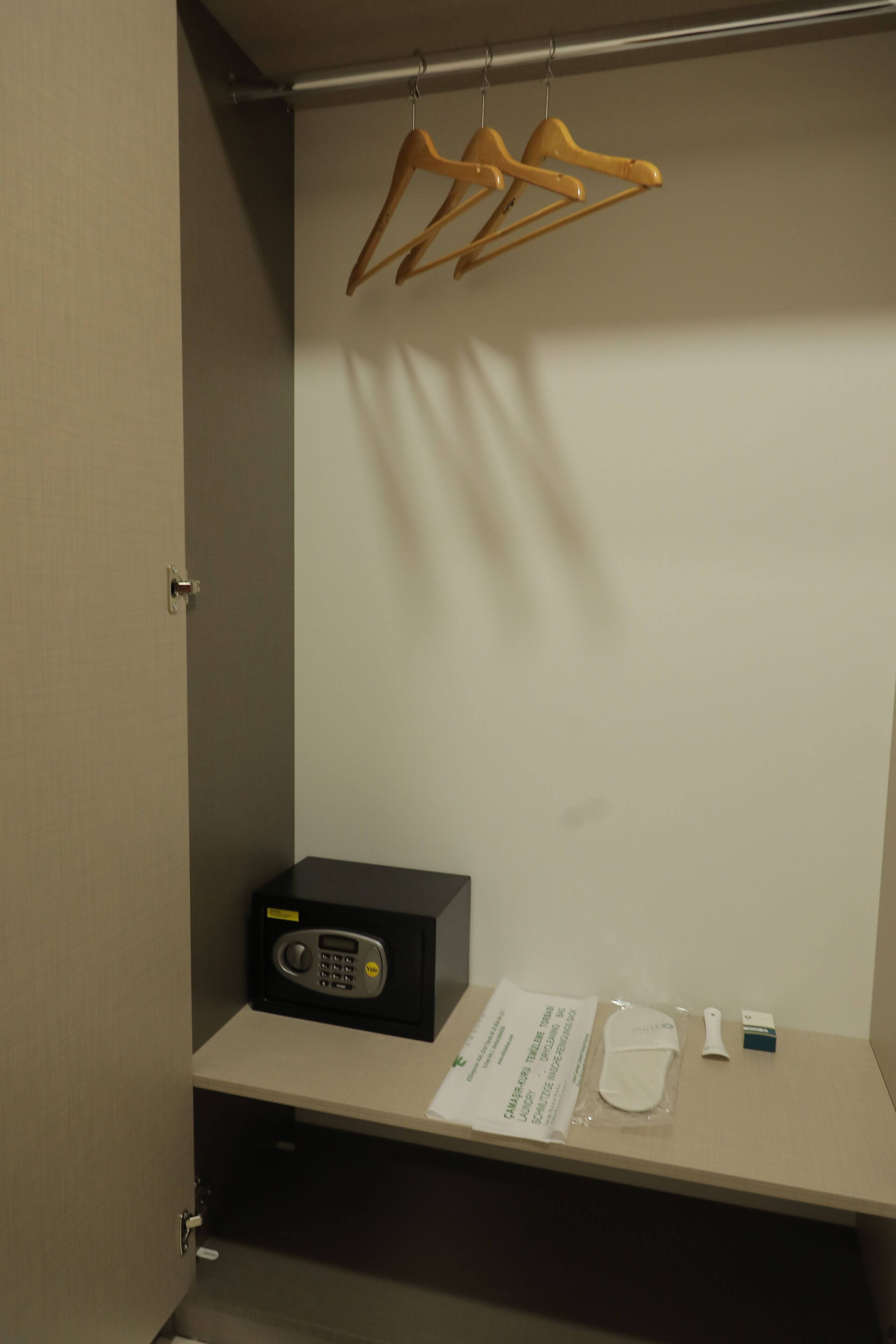 A hotel room with a minibar, a set of wooden hangers, a microwave, and a small table with a tissue box and a packet of tissues.