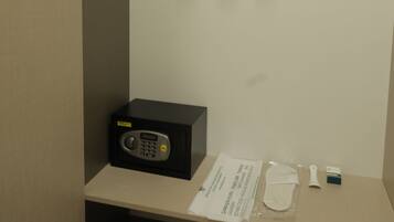 A hotel room with a minibar, a set of wooden hangers, a microwave, and a small table with a tissue box and a packet of tissues.