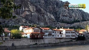 A coastal town with traditional white and red-roofed buildings, a rocky cliff, and a mosque with a minaret. - ELİT OTELHAN (Amasya)
