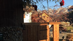 A wooden gate leading to a stone wall with stacked firewood.
