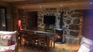 A cozy room with a stone wall, a fireplace, a television, and wooden furniture.