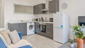 A compact kitchen with a washing machine, oven, and refrigerator. - Central Dudley 1BR Flat w/ Fast Wi-Fi (Dudley)
