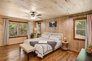 A wooden-paneled bedroom with a bed, bench, bedside table, and a ceiling fan. - Blue Ridge Mountain Views | Hot Tub | Pool Table | Hi-Speed Wi-Fi | Cable (Morganton)