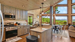 A spacious kitchen with a large island, wooden cabinets, stainless steel appliances, and a view of the outdoors.