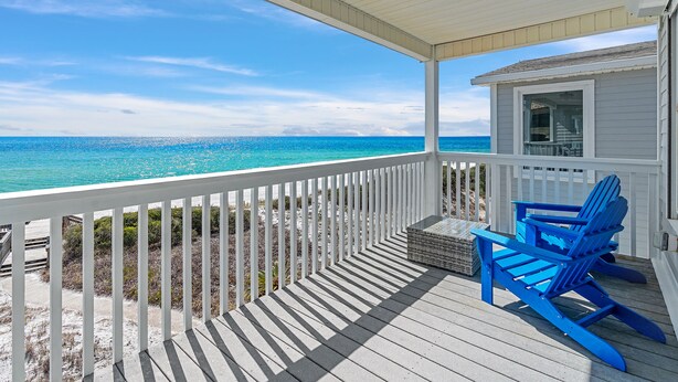 A covered deck with a white railing, a blue Adirondack chair, and a small table. - Gulf View Townhome | Prime Beach Location, Walk to Multiple Restaurants! (Santa Rosa Beach)