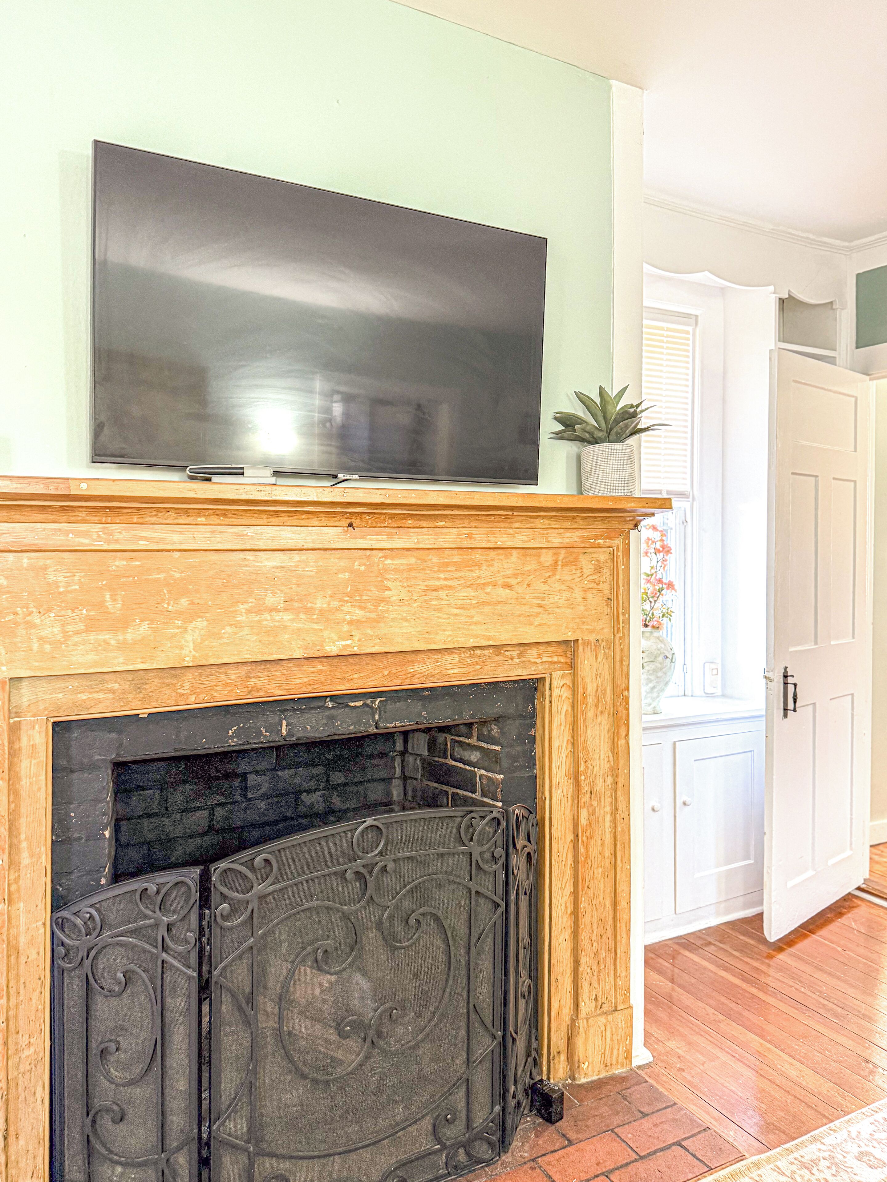 A fireplace with a TV on top, a white door, and a plant on the mantel.