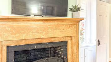 A fireplace with a TV on top, a white door, and a plant on the mantel.