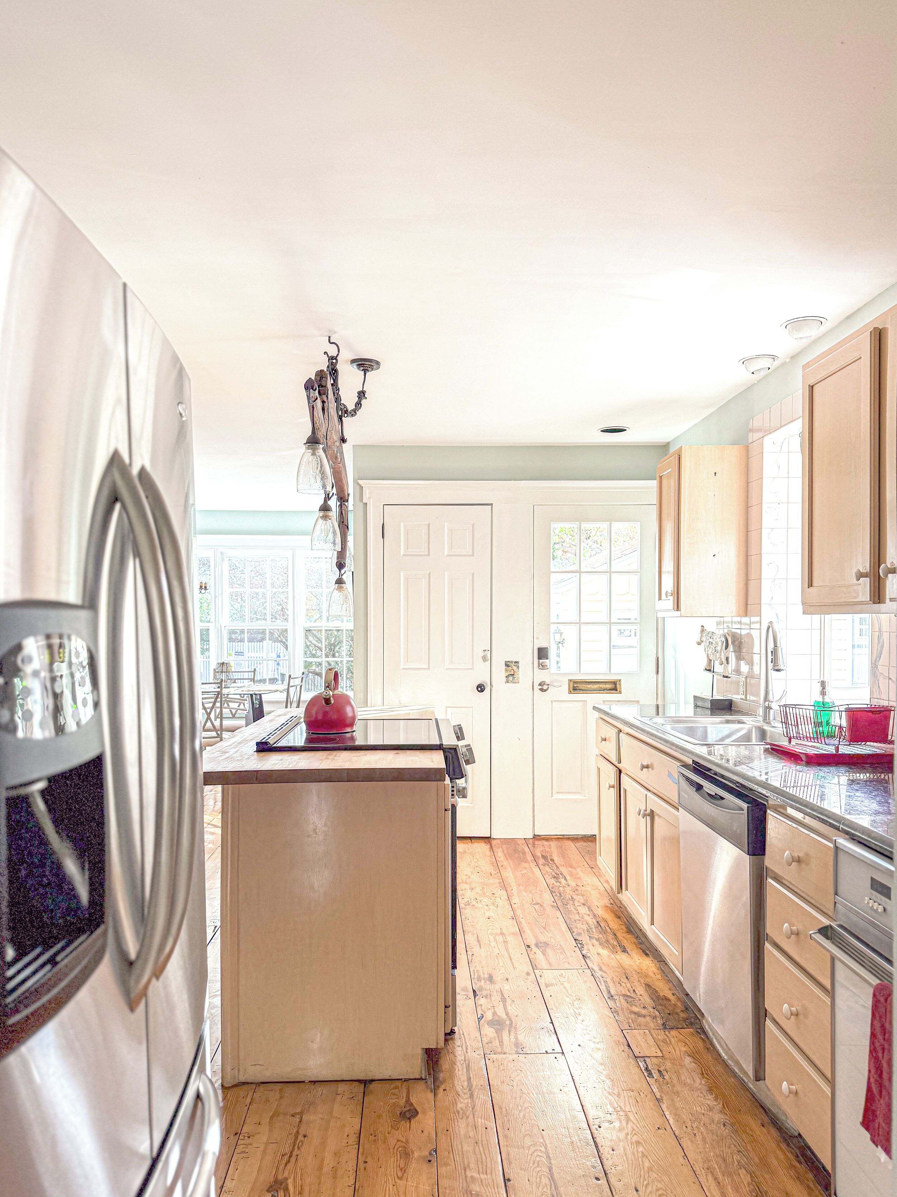 A kitchen with wooden flooring, stainless steel appliances, and a window with a view.