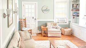 A living room with a beige sofa, a wooden coffee table, and a striped armchair. - Groton Bay / Heated pool opens May 6th 2023! (Groton)