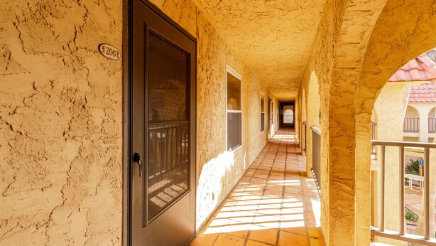 A corridor with a tiled floor, a door with a number plate, and an arched ceiling. - Beachside Cozy Condo | Tropical Pool & Coastal Comfort (Corpus Christi)
