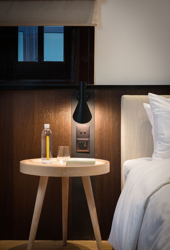 A hotel room with a wooden nightstand, a lamp, a bottle, and a glass. - Shanghai Jinspecial Boutique Hotel (Shanghai)