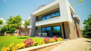 A modern two-story house with a balcony, a play area, and a well-maintained garden. - Hotel Camyuva Beach (Kemer)
