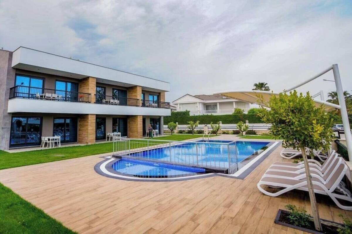 Une maison moderne à deux étages, dotée d’une piscine, d’un espace salon extérieur et d’une pelouse bien entretenue.