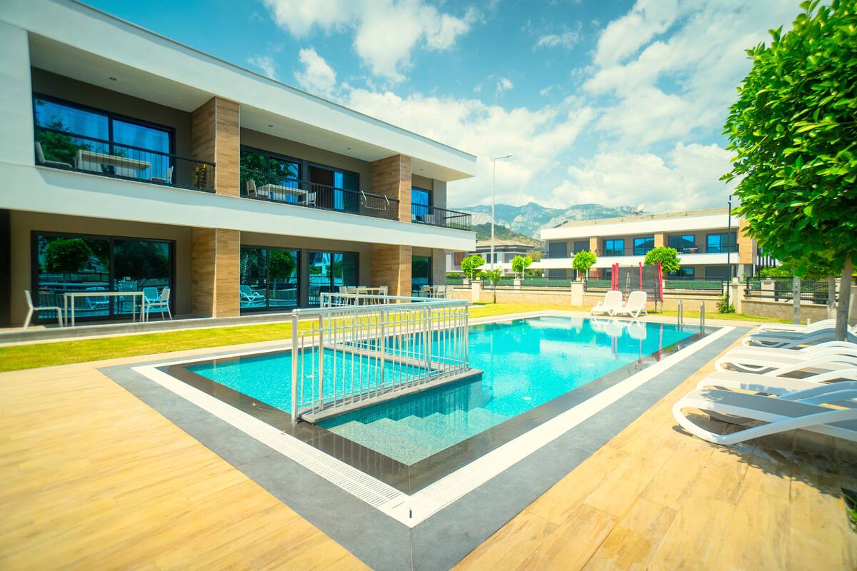 Un hôtel moderne doté d’une piscine, d’un espace extérieur aménagé et offrant une vue sur les montagnes.