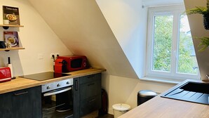 Una cucina moderna con piano di lavoro in legno, forno integrato e microonde rosso.