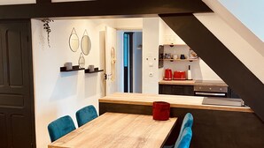 Una cucina moderna con un tavolo in legno e sedie blu, una scala con cornice nera e vista sull'area pranzo.