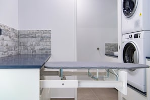 A laundry room with a built-in ironing station and a washing machine.