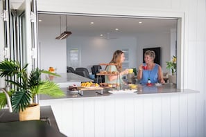 A modern kitchen with a dining area visible through a glass partition.