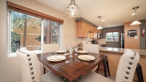Un coin repas avec une table en bois dressée pour quatre personnes, entourée de chaises rembourrées ornées de boutons.