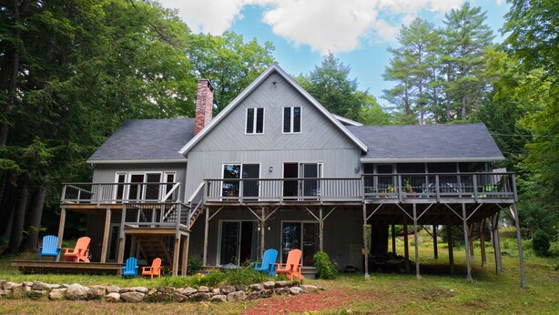 A two-story house with a large deck and a covered porch area.
