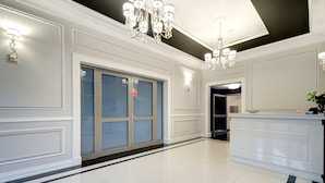 Um hall amplo com piso lustroso, balcão de recepção e um grande candelabro.