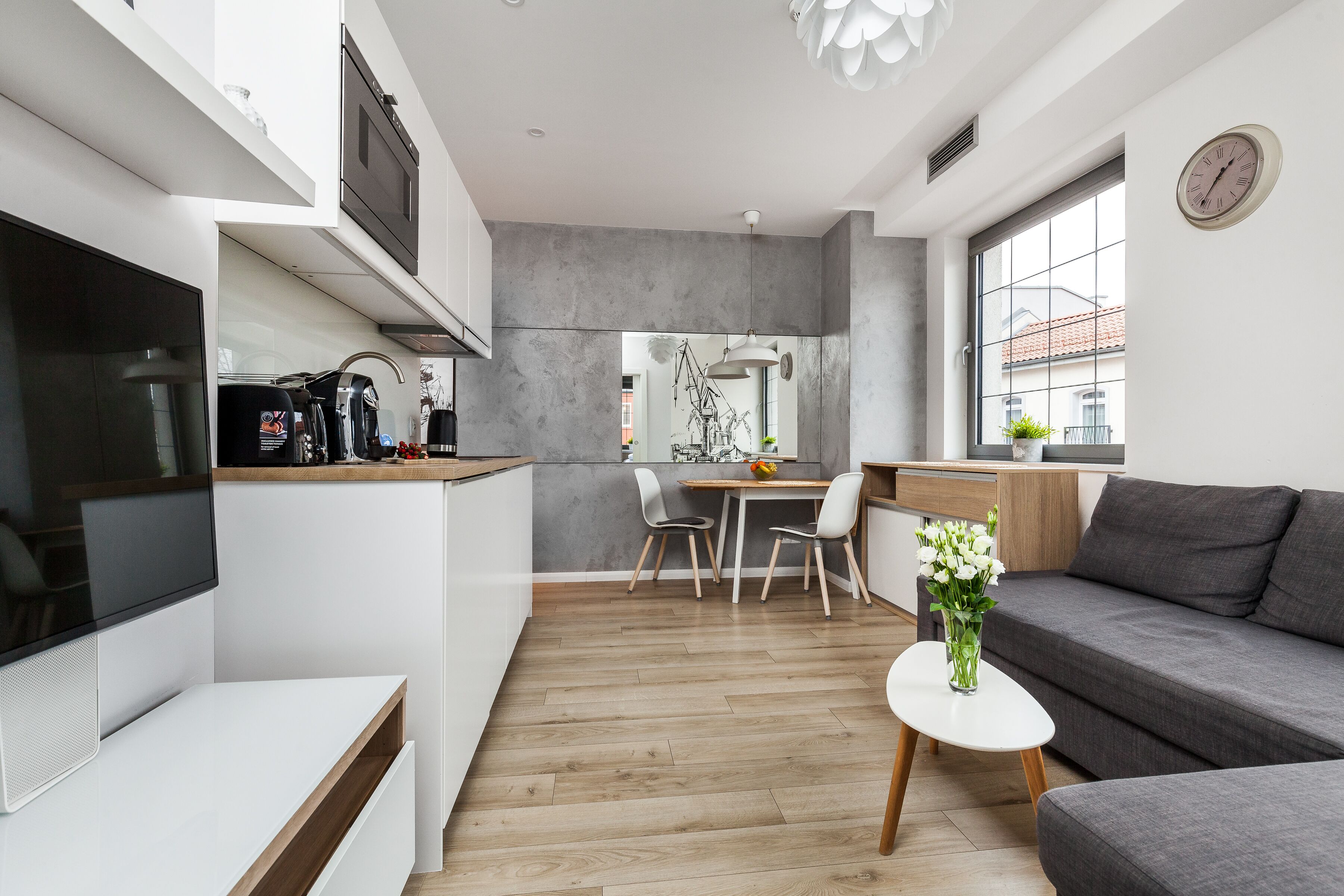 A modern kitchen with a dining area, a sofa, and a TV.