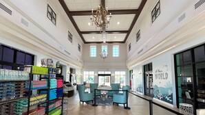 Un hall d’entrée spacieux avec un parquet en point de Hongrie, un lustre et un comptoir d’accueil agrémenté de chaises de couleur turquoise.