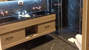 A modern bathroom with a black marble vanity, a glass shower enclosure, and a large mirror. - Miramare Suites (Sestri Levante)