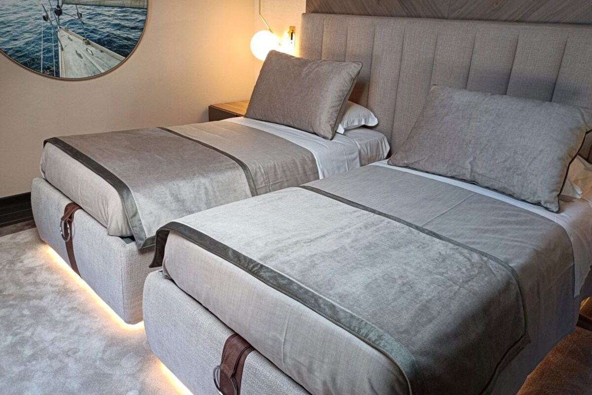 A double bed with a headboard, a bedside table with a lamp, and a round mirror on the wall.