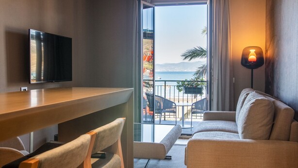 A hotel room with a balcony, a TV, a sofa, and a lamp. - Miramare Suites (Sestri Levante)