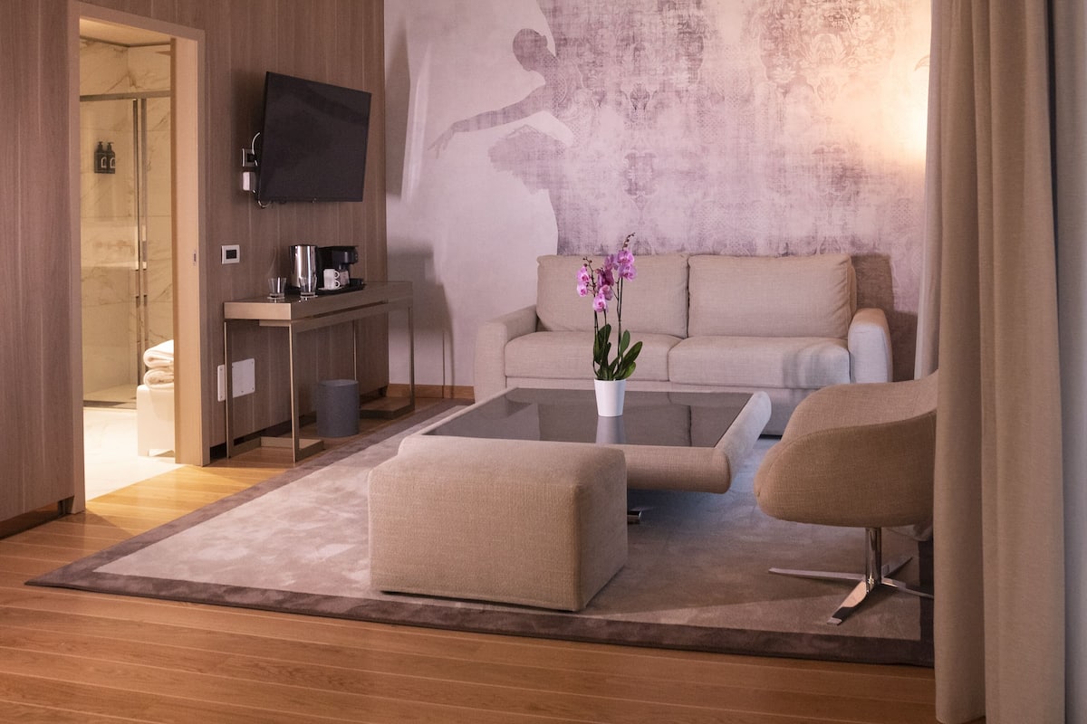 A modern living room with a sofa, coffee table, and a flat-screen TV mounted on the wall.