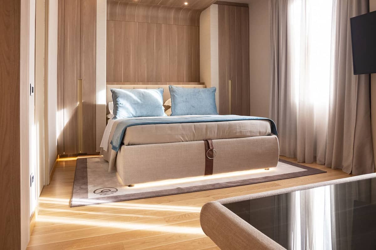 A modern bedroom with a bed, a glass partition, and a view of the outside.