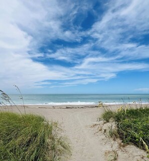 A beach path leading to the ocean with clear skies.