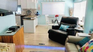 Un salon moderne avec un canapé en cuir et un coin repas comprenant une table et des chaises.