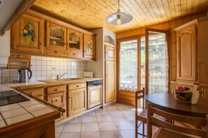 A kitchen with wooden cabinets, a sink, a stove, and a dining area with a table and chairs.
