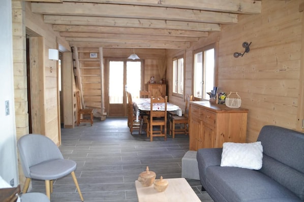 A wooden interior with a dining area, a sofa, and a small table.