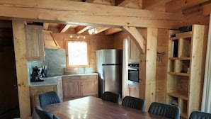 Una cocina de madera con una gran mesa de comedor, armarios empotrados, un refrigerador y un horno.