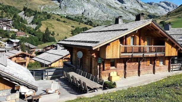 Una cabaña de madera con balcón, rodeada por un paisaje montañoso.
