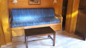 A wooden interior with a blue sofa and a small wooden table.