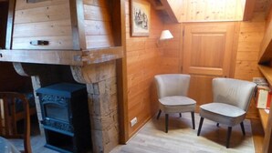 A cozy room with a stone fireplace, two chairs, and a wooden ceiling.