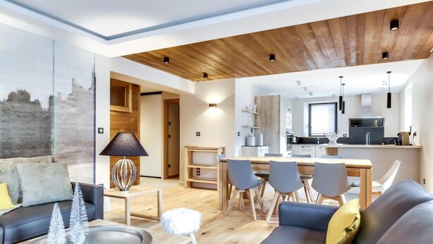 A modern living room with a sofa, dining area, and kitchen. - Wifi, 2nd floor, view street/mountain/village, fitness, sauna, balcony, tv, ski locker, 77m² (Le Grand-Bornand)