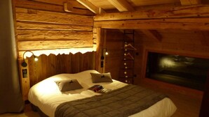 Un dormitorio acogedor de cabaña de madera con una cama, una chimenea y una escalera.
